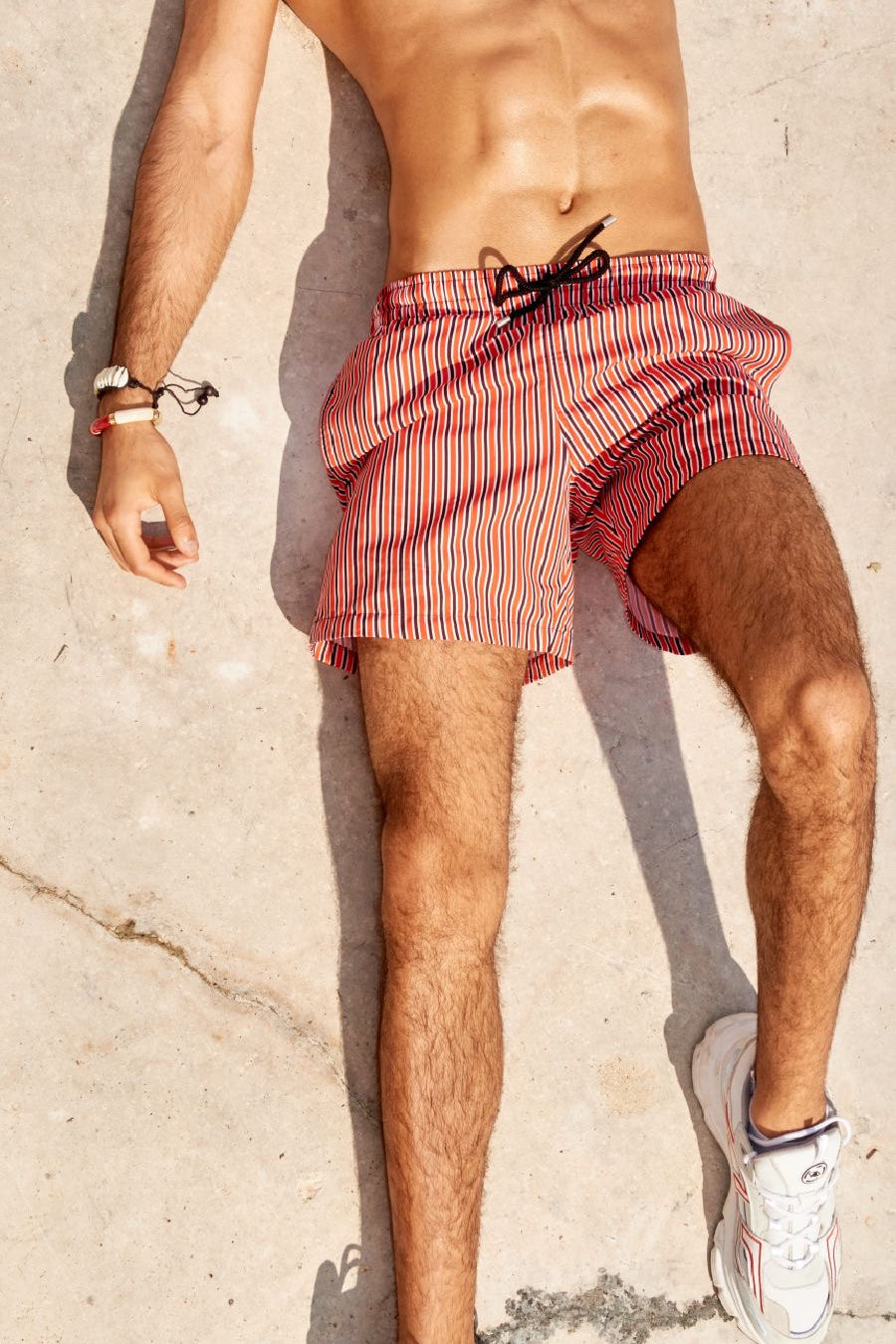 Photo rapprochée du short de bain rouge rayé avec cordon noir à la taille.