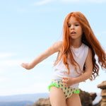 Photo d'une petite fille à la mer portant la culotte de maillot de bain Lolo avec des homards bleus et des froufrous verts sur les côtés
