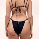 Photo d'une femme de dos portant le haut de maillot de bain Remini en noir