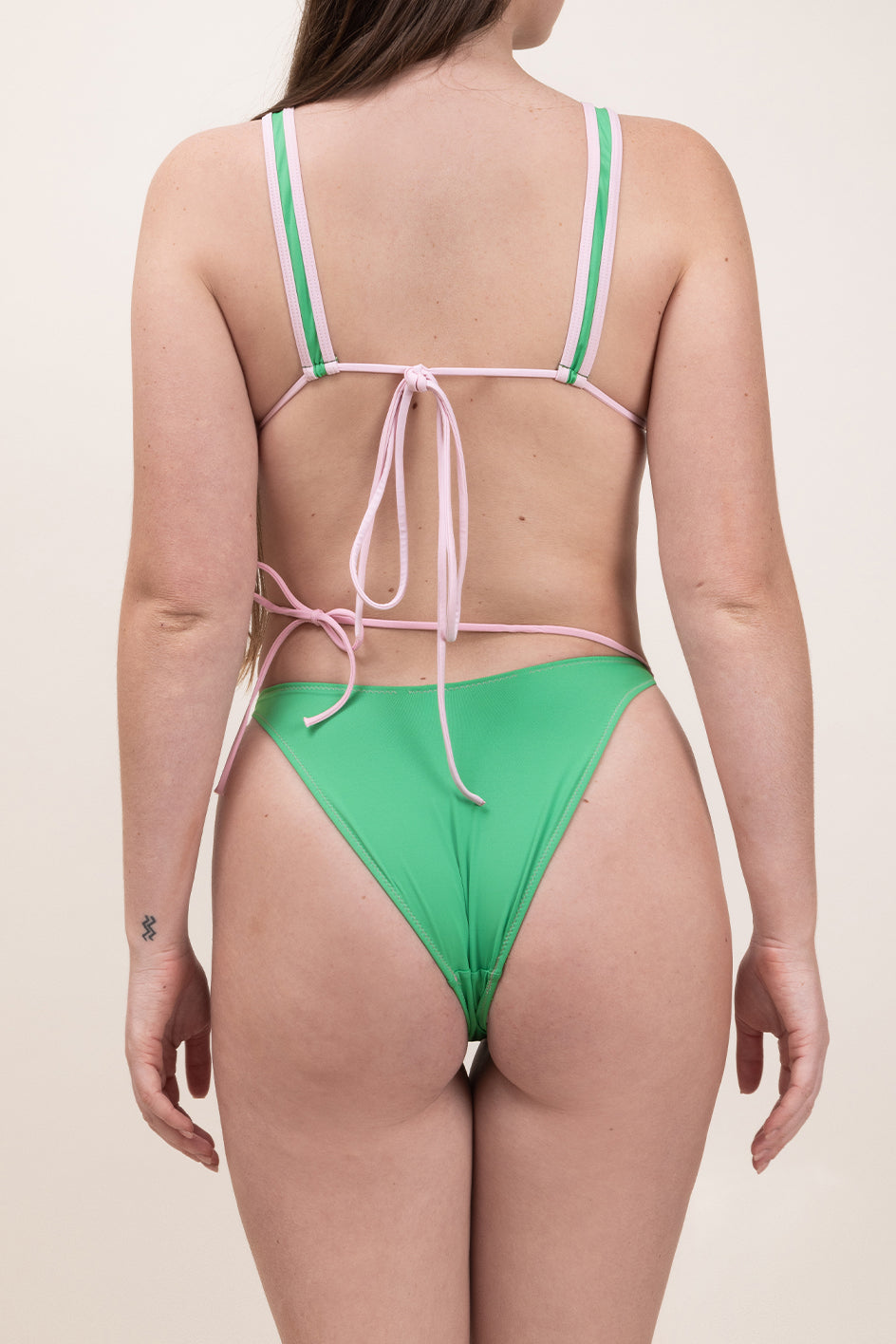 Photo d'une femme de dos portant le bas de maillot de bain Tiana en rose blush et vert matcha