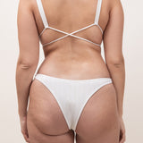 Photo de dos d'une femme portant le haut de maillot de bain Bianca en couleur ivoire en matière jacquard, avec les ficelles croisées dans le dos