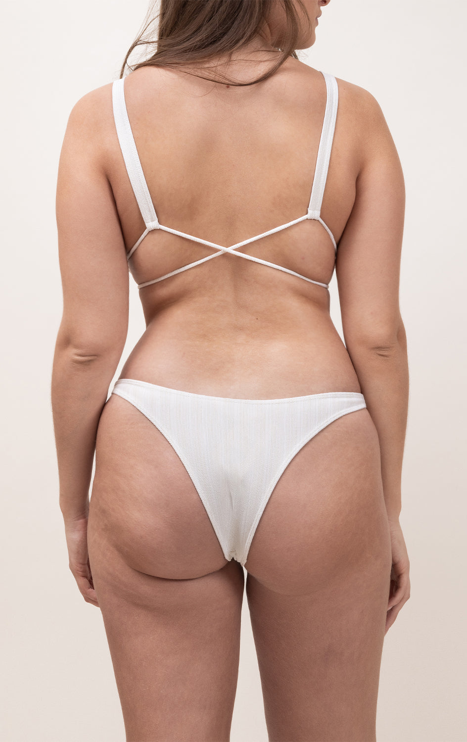 Photo de dos d'une femme portant le bas de maillot de bain Tanga en ivoire jacquard.