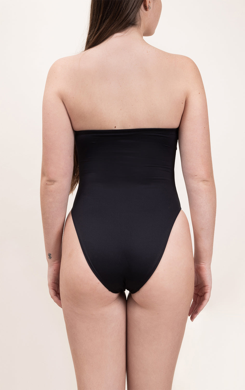 Photo d'une femme de dos sur fond blanc portant le maillot de bain une pièce Cala Rossa noir