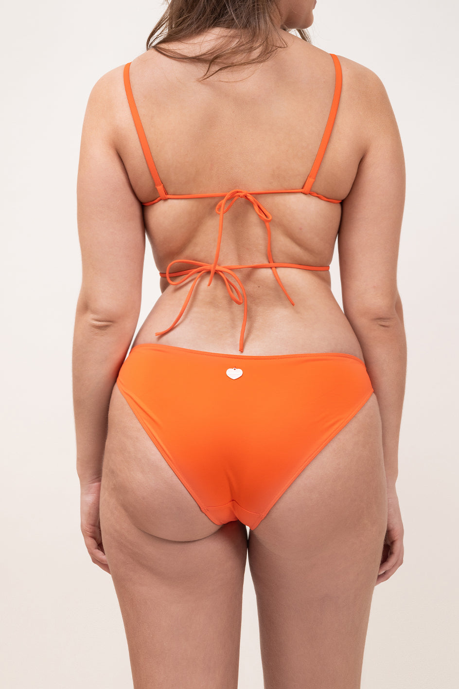 Photo d'une femme à forte poitrine de dos portant le haut de maillot de bain Ponza en orange