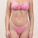 Photo de face d'une femme portant le bas de maillot de bain Tanga en rose vichy.