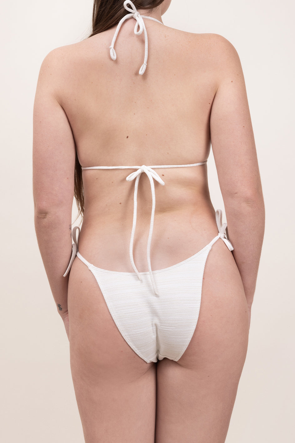 Photo de dos d'une femme portant le haut de maillot de bain Talita en blanc jacquard