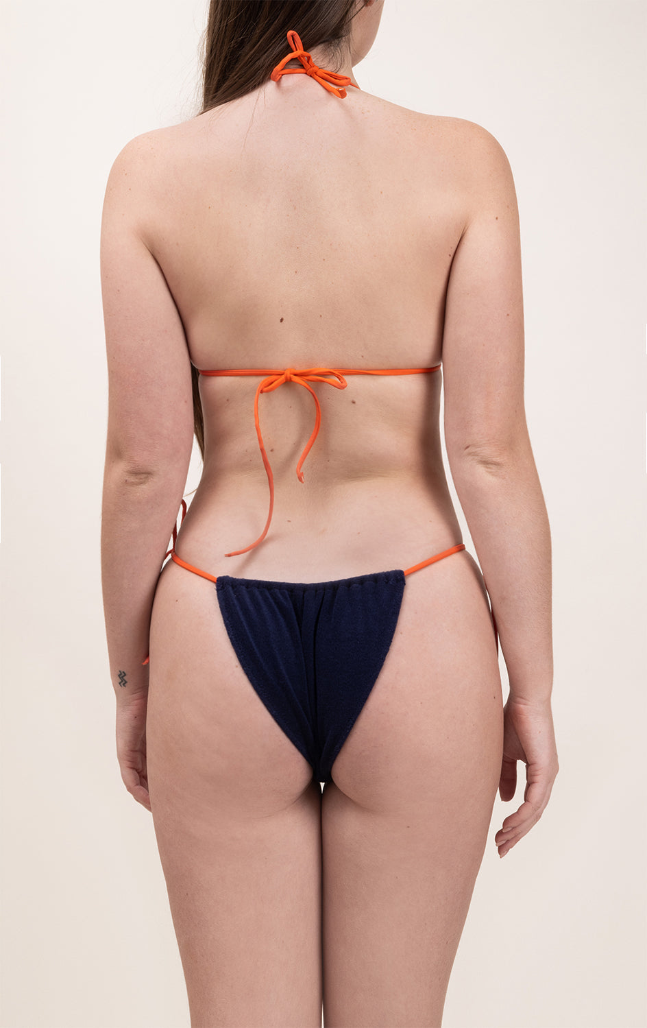 Photo de dos d'une femme portant le haut de maillot de bain Talita en tangerine et matière éponge