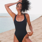 Photo de face d'une mannequin à la plage portant le maillot de bain une pièce Marmi noir