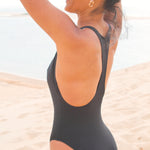 Photo de côté d'une mannequin à la plage portant le maillot de bain une pièce Marmi noir