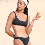 Photo d'une mannequin à la plage portant le haut de maillot de bain Twin Palm noir rayé