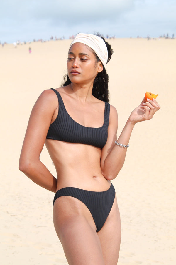 Photo d'une mannequin à la plage portant le haut de maillot de bain Twin Palm noir rayé