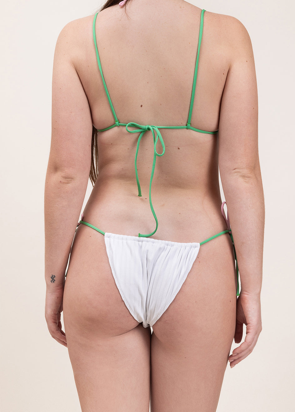 Photo de dos d'une femme portant le maillot Alaior blanc avec les bretelles vertes
