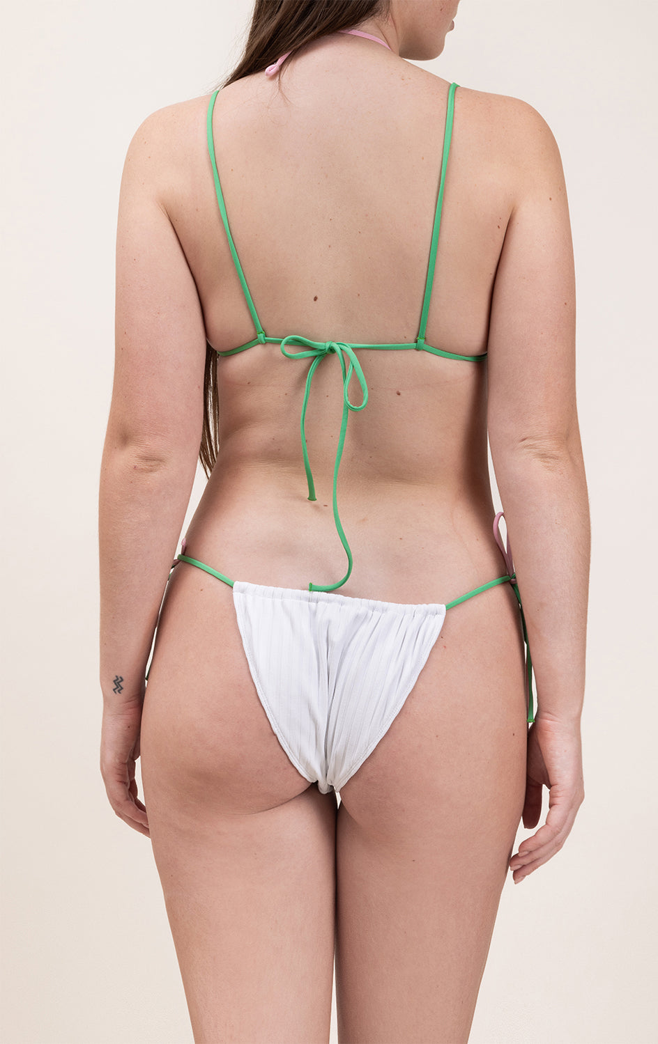Photo d'une femme de dos portant le haut de maillot de bain Remini en blanc stripped