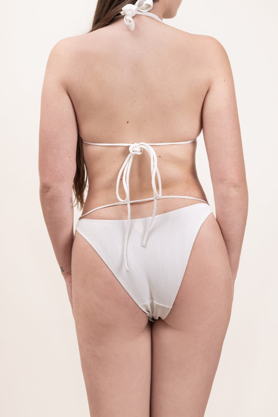 Photo d'une femme de dos portant le bas de maillot de bain Tiana en ivoire jacquard