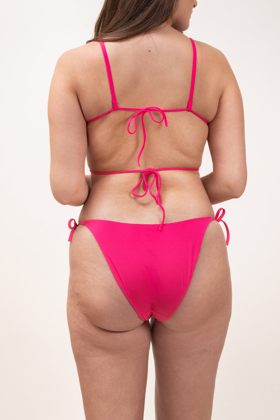 Photo d'une femme à forte poitrine de dos portant le haut de maillot de bain Ponza en rose saphire