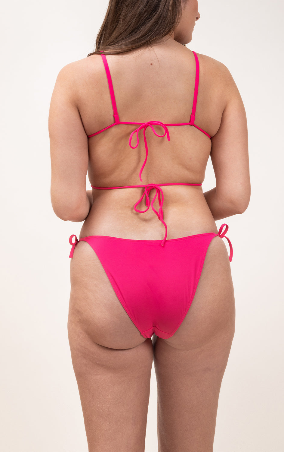 Photo d'une femme à forte poitrine de dos portant le haut de maillot de bain Ponza en rose saphire