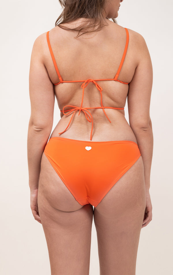 Photo d'une femme à forte poitrine de dos portant le haut de maillot de bain Ponza en orange