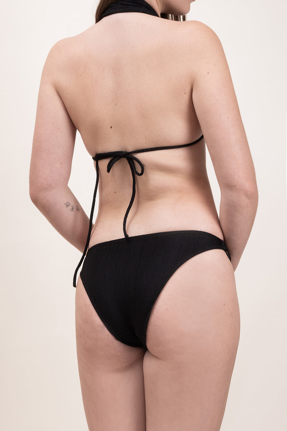 Photo de dos d'une femme portant le haut de maillot de bain Bianca en couleur noire et en matière jacquard