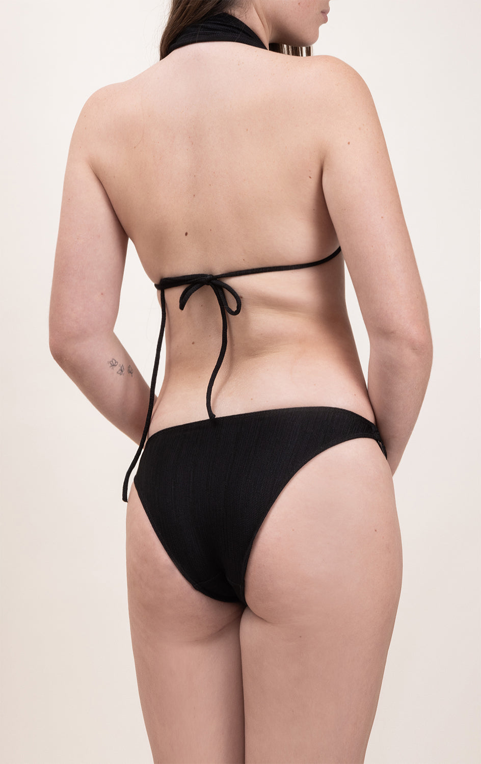 Photo d'une femme de dos portant le bas de maillot de bain Serena en noir jacquard