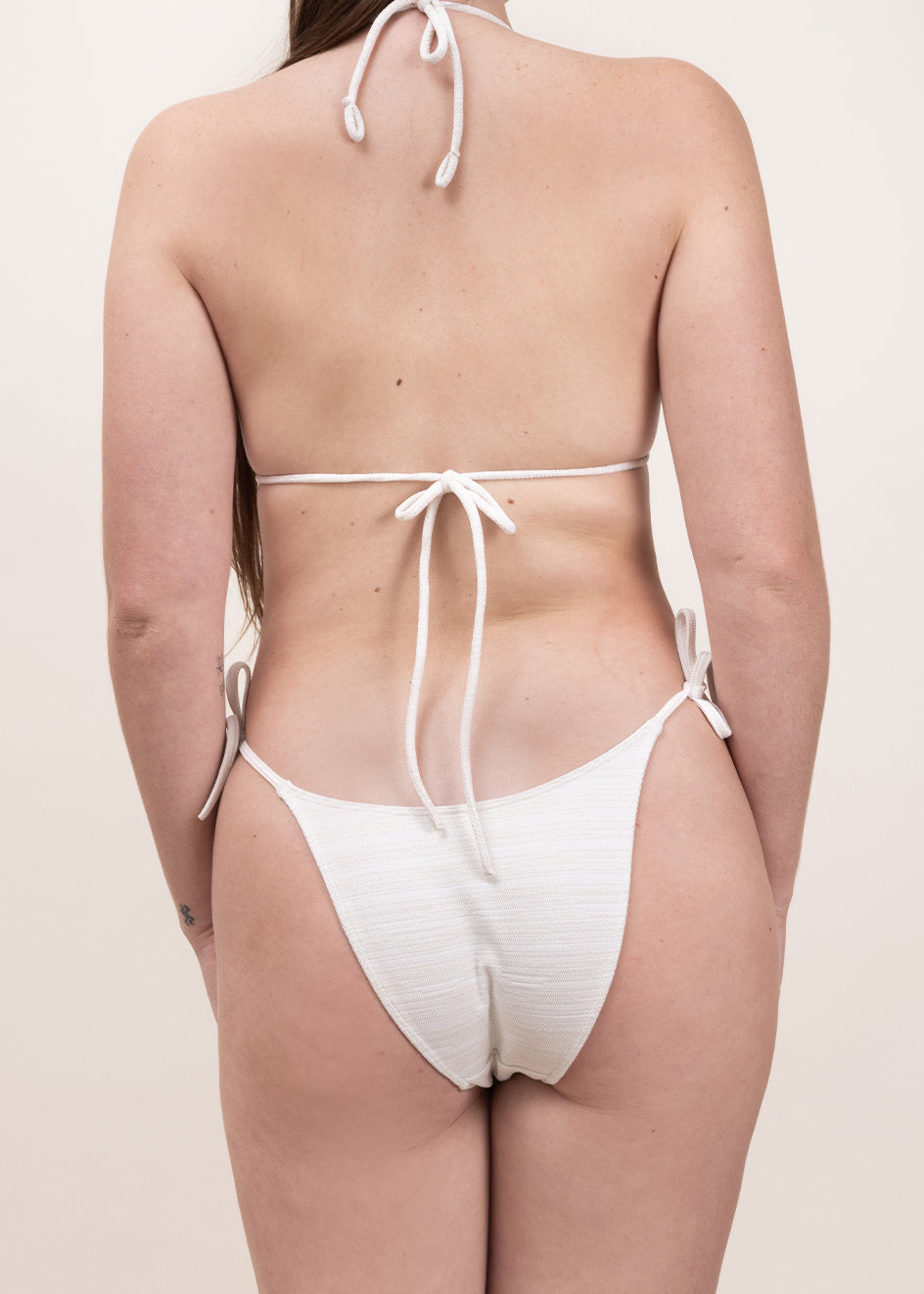 Photo d'une femme de dos portant le bas de maillot de bain Monterosso ivoire jacquard
