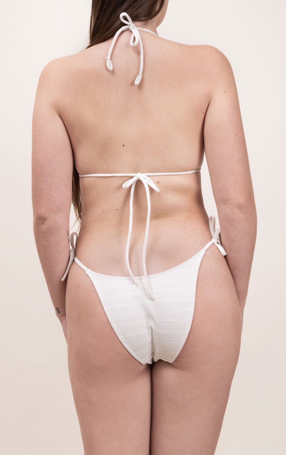 Photo de dos d'une femme portant le haut de maillot de bain Talita en blanc jacquard