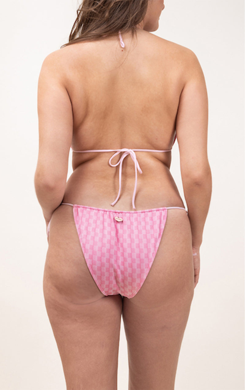 Photo de dos d'une femme portant le maillot de bain Alaior rose à motif Vichy, et à bretelles et ficelles roses claires. 